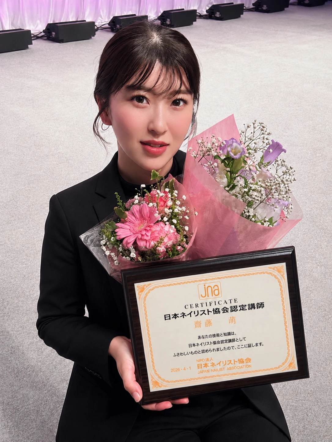 花束とJNA日本ネイリスト協会認定講師の認定証を手にする、MIYABI主宰の齋藤萌